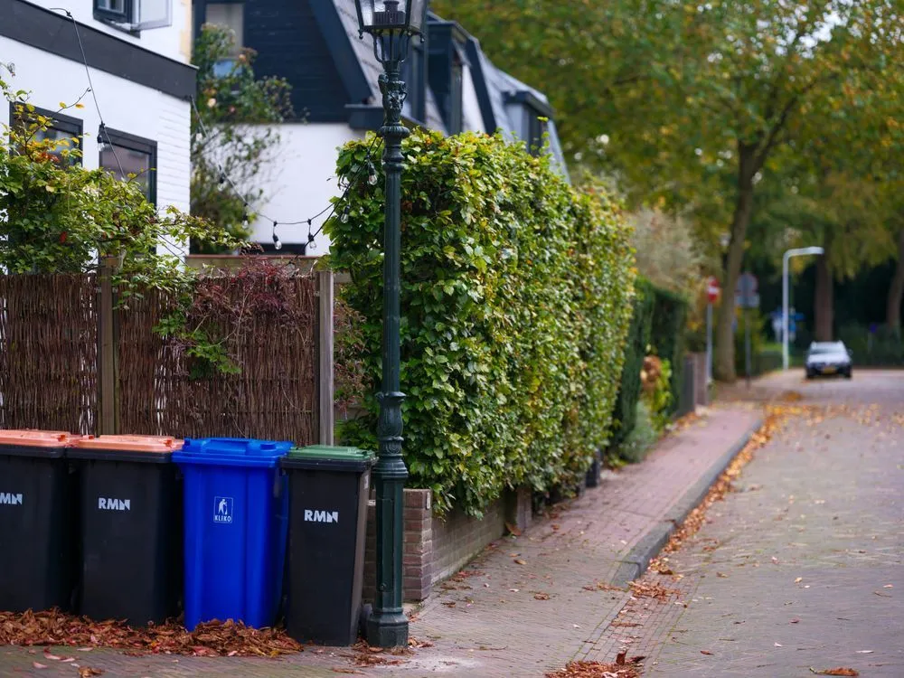 Large metal recycling roll-off bin equipped with GPS tracking device for automated fleet management and location monitoring